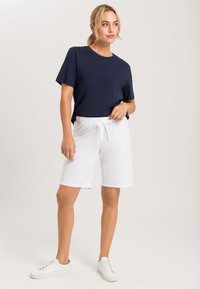 Námořnické tričko s krátkým rukávem spárované s bílými šortkami na elastický pas. Model má na sobě bílé tenisky. Hladká tkanina, volný střih.