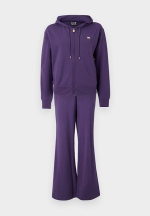 Purple tracksuit with a zip-up hoodie and flared pants. Soft fabric, gold hardware accents, and front pockets. Simple, modern design.