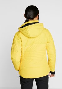 Gelbe Puffjacke mit schwarzen Akzenten, Kapuze und gestepptem Muster. Verfügt über elastische Ärmelöffnungen und eine taillierte Silhouette.