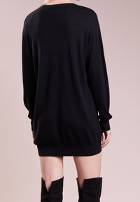 Mustat neulottu mekko pitkähihaisilla, röyhelöillä hihoissa ja helmassa, rento istuvuus, pehmeä rakenne ja hienovarainen kiilto.