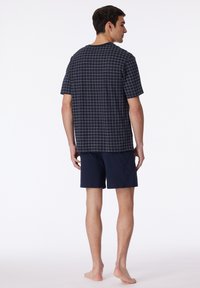 Navy short-sleeve shirt with beige grid pattern, paired with solid navy shorts, showcasing a relaxed fit and soft cotton material.