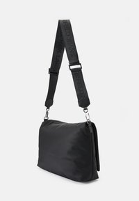 Borsa a spalla nera in nylon con una struttura morbida e imbottita. Presenta una tracolla regolabile con logo in rilievo e dettagli in metallo argentato.