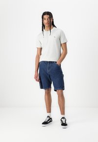 Grå crew neck t-shirt, denim cargo shorts med sidelommer og sorte sneakers. Enkel design, afslappet pasform med et tekstureret stof.