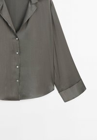 Chemise gris foncé à manches longues avec boutons, col et manches à revers, présentée sur un fond blanc.
