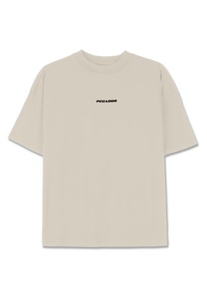 Light beige cotton t-shirt with short sleeves, relaxed fit, and a black "PEGADOR" logo printed on the front. Smooth texture, crew neck.