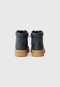 Stivaletti alla caviglia blu navy e neri con un upper in pelle testurizzata, tacco rinforzato e suola in gomma beige con pattern antiscivolo.