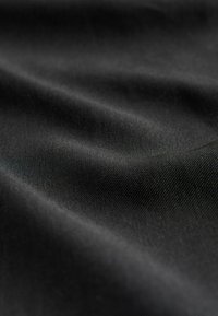 Musta kangas, sileä pinta, lievästi heijastava, jossa on näkyvä hieno kudontakuvio ja lempeät poimut, jotka luovat syvyyttä.