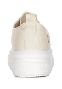Beżowy płócienny sneaker widoczny z tyłu z grubą białą gumową podeszwą i materiałową pętelką na pięcie.