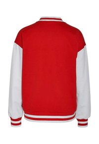 Sweatshirt rouge et blanc avec un col rond, des poignets côtelés et des accents rayés. Le design présente un tissu rouge au niveau des épaules et des manches.