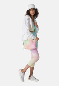 Pastellfärgade leggings och en croptopp matchar med en vit huvtröja med dragkedja. En matchande mjukt färgad crossbody-väska och vita sneakers fulländar looken.