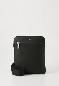 Svart lærveske med teksturert overflate, med glidelås på toppen, glidelåslomme foran og avtagbar stropp. Glatte metalldetaljer.