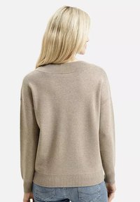 Jasno beżowy sweter, prążkowany dekolt i mankiety, miękka tekstura, nieco luźny krój, gładki design, widok z tyłu.