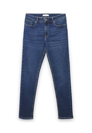 Jean en denim bleu foncé avec une coupe slim, cinq poches et des coutures visibles. Le tissu semble doux avec une légère élasticité.