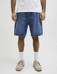 Shorts in denim con una vestibilità rilassata, colore azzurro chiaro e orlo sfrangiato. Abbinati a calze bianche e scarpe beige per un contrasto.
