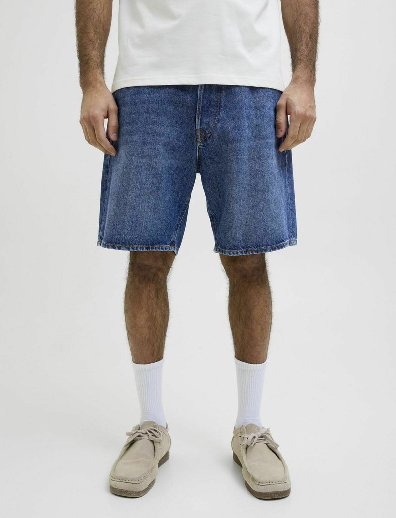 Shorts in denim con una vestibilità rilassata, colore azzurro chiaro e orlo sfrangiato. Abbinati a calze bianche e scarpe beige per un contrasto.