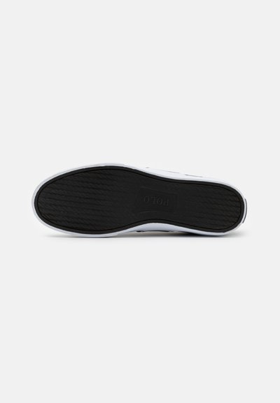 Hvite sneakers med svart gummisåle, med et teksturert mønster og logodetalj, designet for hverdagsbruk med lav-top profil.