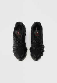 Fekete Nike Shox sportcipők texturált felsőrésszel, hálós panelekkel és párnázott talppal. Fűzőrendszerrel és a nyelvén található jellegzetes logóval rendelkezik.