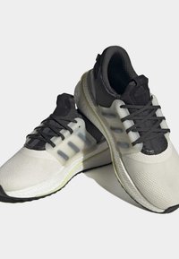 Hvide og sorte atletiske sko med tekstureret stof, gennemsigtige accenter og en polstret sål. Har sorte snørebånd og logo-detaljer.