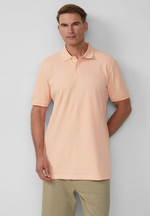 Polo shirt pêche clair avec un col, des manches courtes et un petit logo sur la poitrine. Assorti à un pantalon gris clair. Texture lisse.