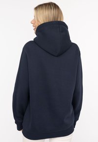 Granatowy hoodie z dużym kapturem, długimi rękawami i luźnym krojem. Wykonany z miękkiego materiału, z prążkowanymi mankietami i dolnym wykończeniem.