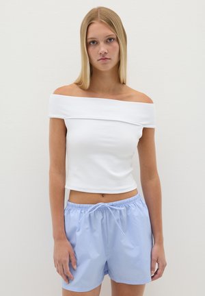 Weißes, schulterfreies Oberteil mit kurzen Ärmeln, kombiniert mit hellblauen gestreiften Shorts mit Kordelzug. Glattes Material und lockere Passform.