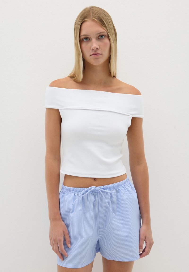 Top blanco sin mangas con tirantes cortos, combinado con pantalones cortos de rayas azules claros con cordón. Tela suave y corte relajado.