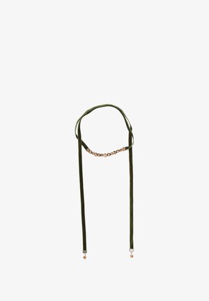 Zelený sametový náhrdelník s centrálním pruhem obdélníkových zlatých akcentů a visícími detaily, s hladkou textura a nastavitelnými šňůrkami.