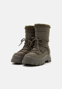Botas impermeables verdes con parte superior acolchada, cuello de pelaje y suela de goma gruesa y resistente con profundos tacos para un mejor agarre.