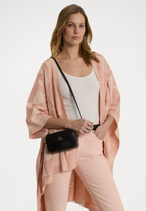 Cardigan leggero rosa a fantasia indossato sopra una canotta bianca, abbinato a pantaloni rosa chiaro e a una piccola borsa a tracolla nera con dettagli dorati.