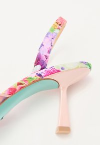 Sandale à talons florale avec une tige en tissu rose et multicolore. Dotée d'une semelle intérieure vert menthe et d'un talon rose fin.