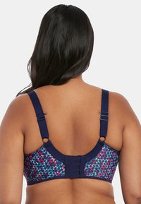 Achteraanzicht van een bh met een geometrisch patroon in levendige kleuren, marineblauwe bandjes, verstelbare haakjes en een gestructureerde stof.
