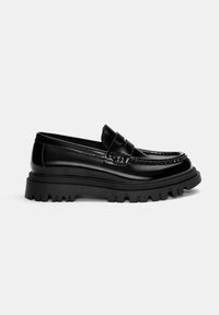 Mocassino in pelle nera con suola in gomma spessa, dotato di una fascia decorativa e dettagli di cucitura sulla parte superiore per un tocco di consistenza.