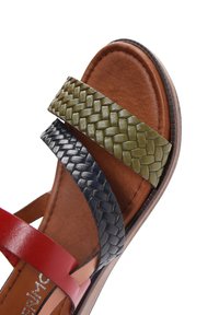 Sandale en cuir tressé avec des lanières rouge, marine et vert olive, semelle intérieure marron et semelle lisse avec un bord brun clair.