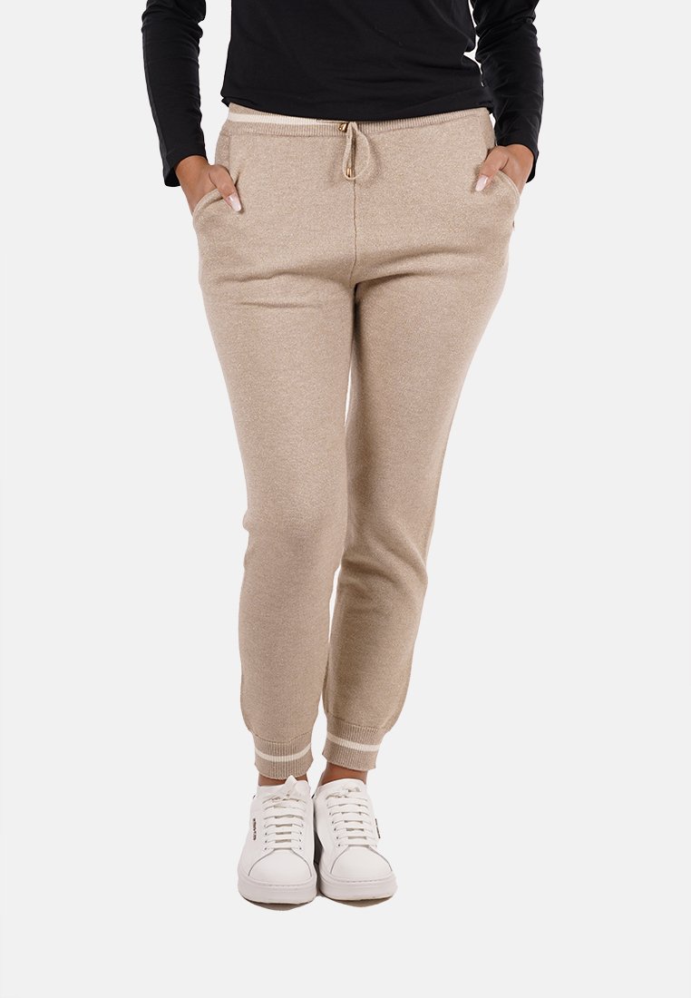 Pantaloni jogger beige con cintura elastica e lacci, dotati di due tasche laterali e polsini a coste, abbinati a sneakers bianche.