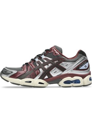Zapatilla deportiva con una parte superior de malla y sintético en gris y burdeos, con acentos en negro, una suela acolchada y unidades de aire visibles.