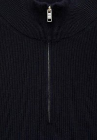 Schwarzer gerippter Strickpullover mit hohem Kragen und einem silbernen Reißverschluss an der Vorderseite. Eng gestrickte Textur mit vertikalen Linien.