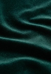 Hlboká zelená látka s hladkou textúrou, s jemnými záhybmi a mäkkým leskom, vytvárajúca bohatý a elegantný vzhľad.