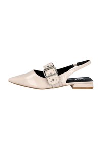 Zapato slingback de charol beige con punta afilada, tacón grueso y hebilla decorativa con tachuelas en la correa. Forro interior negro.