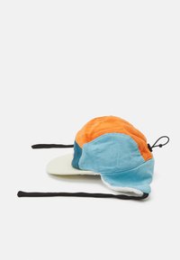 Color-blocked corduroy hat with an orange, blue, and green design; features a brim and adjustable black straps. Soft texture and distinct shape.