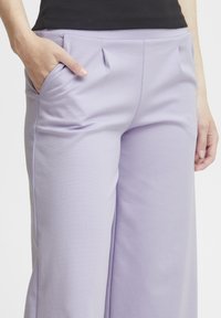 Lavendel wijde pijpen broek van zachte stof, met plooien en zijzakken, met een gladde textuur en strakke lijnen.