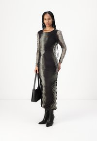 Rochie cu mânecă lungă, ajustată, de culoare verde închis și negru ombre, cu textura plisată. Complementată cu cizme negre cu toc înalt și o geantă.