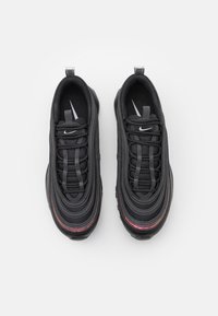 Black athletic shoes with textured mesh upper, rubber sole, feature black laces, and a small white Nike logo on the tongue.