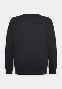 Il sudore di cotone nero presenta un colletto a girocollo, polsini e vita a coste. Texture liscia con dettagli di cucitura minimi e senza grafiche.