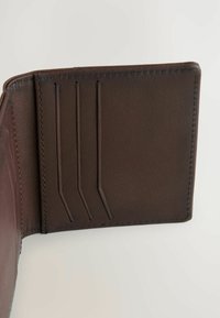 Brun læderpung indeni med tre kortlommer, glat tekstur, syede kanter og et minimalistisk design.