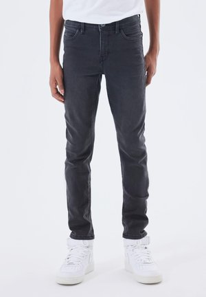 Jeans in denim nero con fitting slim, design a cinque tasche e una leggera sfumatura. Abbinati a sneakers bianche alte.