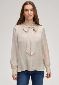 Beige zijden blouse met een striksluiting bij de hals, lange mouwen met knoopmanchetten, een gladde textuur en een licht afgeronde zoom.
