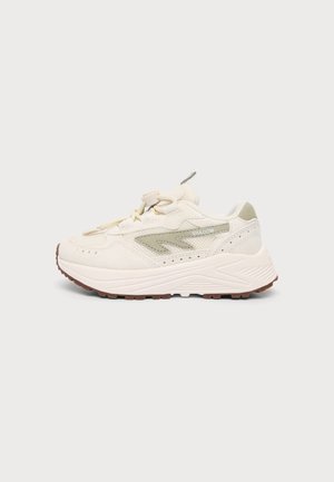 Krem- og beige afslappet sneaker med tyk sål, snørelås og tekstureret gummisål, vist fra siden på en ensfarvet baggrund.
