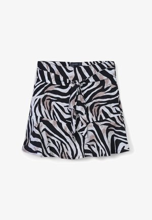 Jupe mini à motif zèbre noir et blanc avec un nœud à l'avant et un ourlet évasé, taille petite, étiquette de marque visible sur la taille.