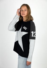 Dark navy knit sweater with light gray star design, gray sleeves, and white text "GRC" and "12" on front. Soft texture, relaxed fit.