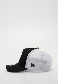 Fekete és fehér baseball sapka hálós hátsó résszel, ívelt sárral és logóval az oldalon. Texturált anyag és strukturált kialakítás.